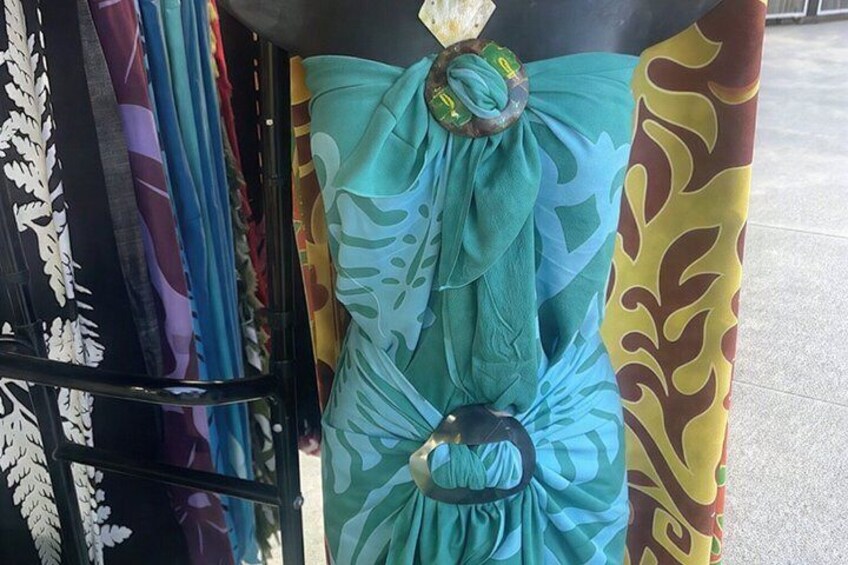 A mannequin dressed in a teal dress with floral patterns and a large bow. 2