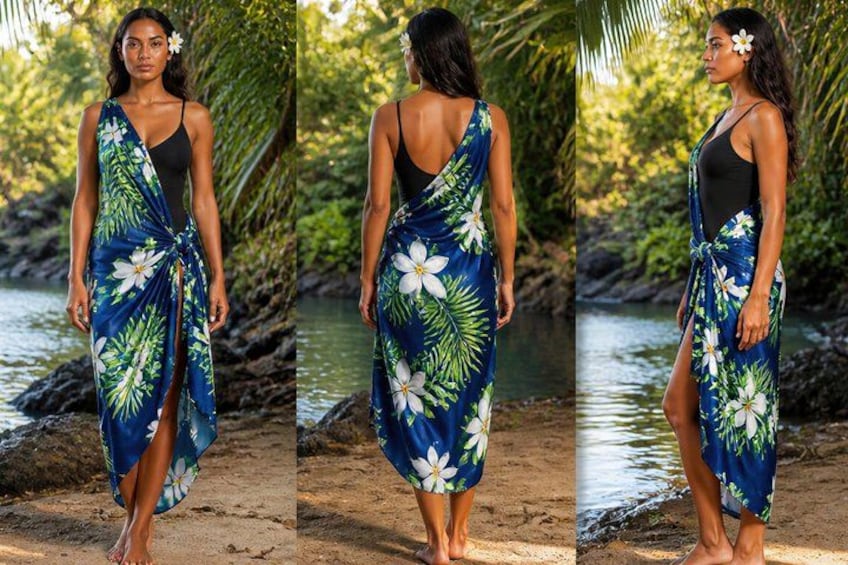 A woman wearing a blue floral wrap dress with a tie detail, standing on a sandy path near a body of water with greenery in the background. 4