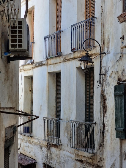 A weathered building with multiple balconies, a hanging air conditioner, and a street lamp. 3