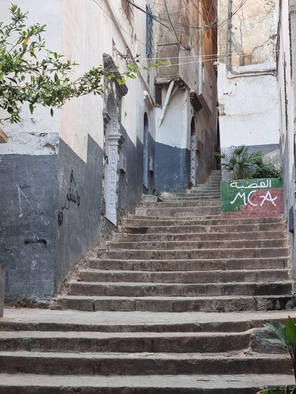 A set of stone steps leading up to a building with a sign in Arabic. 1