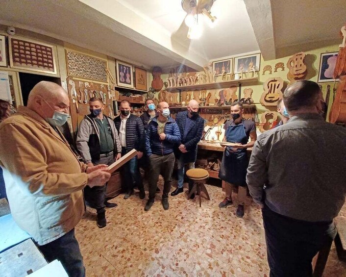 A group of people in a room with wooden instruments on display. 2