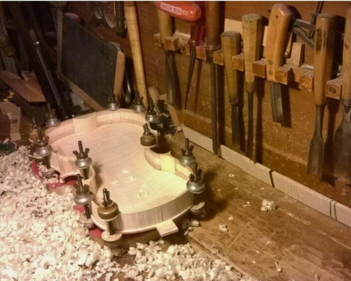 A woodworking bench with a circular workpiece surrounded by various tools and clamps. 4