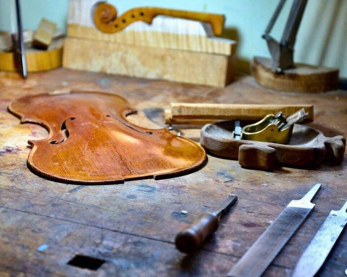 A violin on a wooden surface with tools and a bow nearby. 1