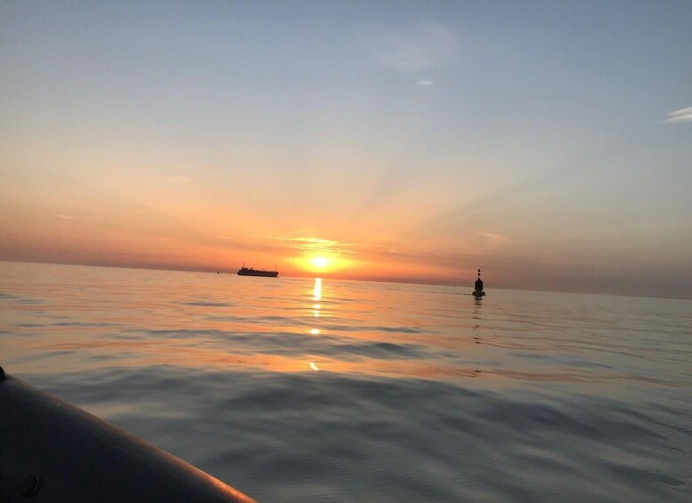 A calm sea at sunset with a ship and a buoy in the distance. 3