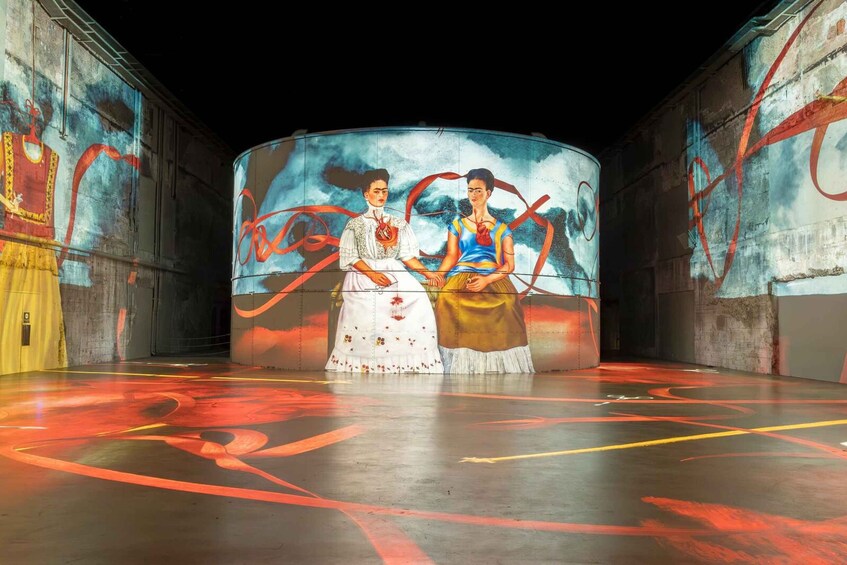 A performance stage with a large circular screen displaying a painting of two figures. 4