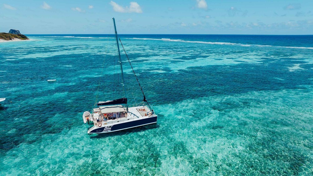 A sailboat anchored in clear turquoise waters with a rocky island in the background. 4