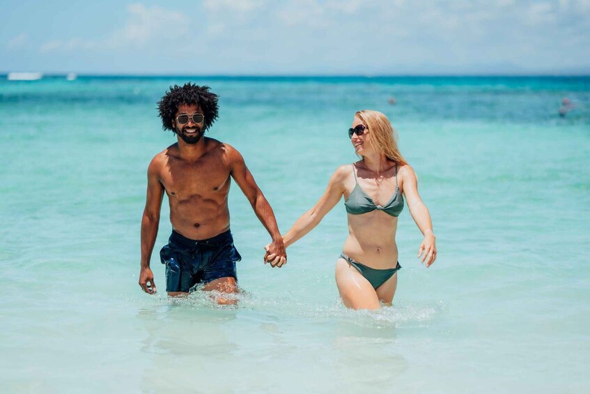 A man and a woman walking hand in hand in shallow water. 2