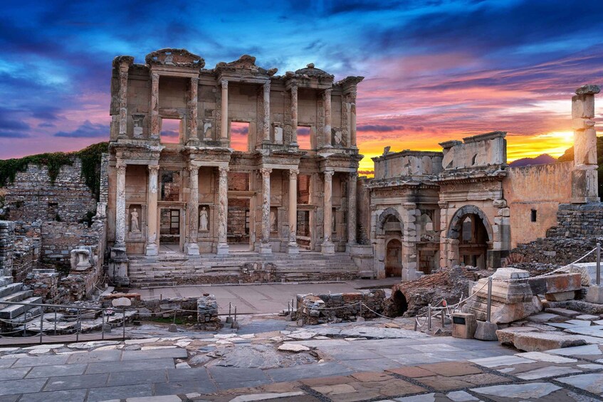 Ancient ruins with columns and statues, set against a sunset sky. 2