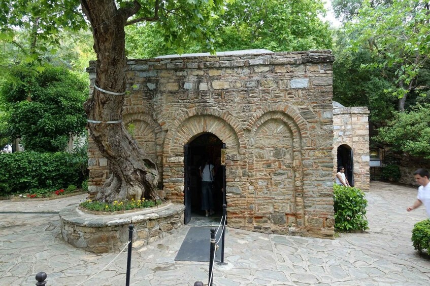 A stone structure with an arched entrance, surrounded by greenery and a paved path. 3