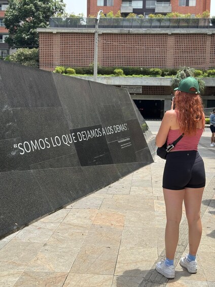 A person standing in front of a wall with a quote in Spanish. 4