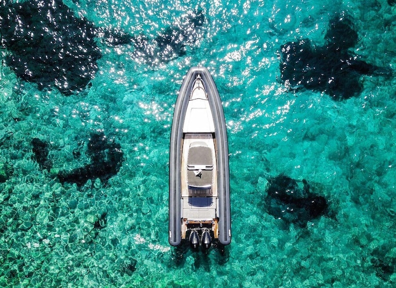 A boat on clear turquoise water with visible underwater rocks and coral formations. 4