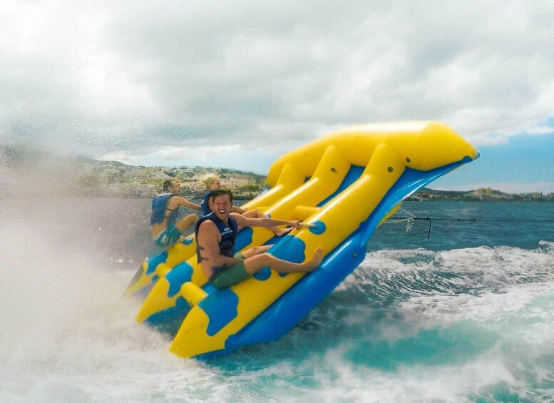 A person riding a yellow and blue inflatable raft on water. 3