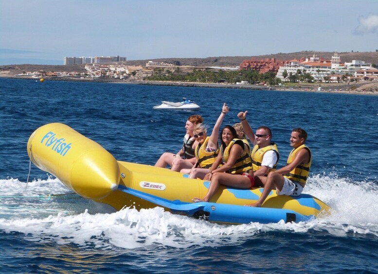 A group of people on a yellow inflatable raft with blue accents, floating on a body of water. 1