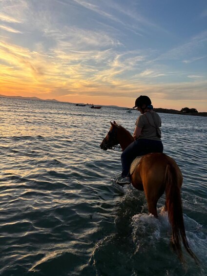 Une personne à cheval traversant une étendue d’eau au coucher du soleil. 4