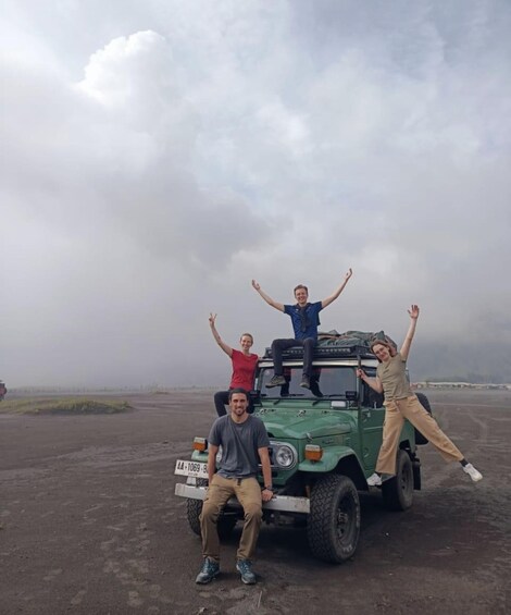 Three people posing with a green off-road vehicle on a dirt road. 3