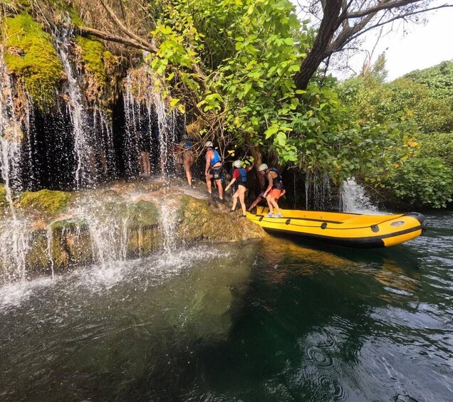 A group of people in a yellow raft at the edge of a waterfall. 2