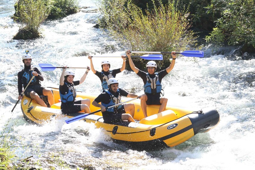 A group of people in a yellow raft navigating a river with rapids. 5