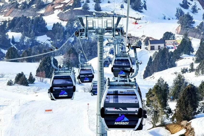 Un telesilla con cabinas que dicen 'AMIRSOY' subiendo una montaña nevada. 2