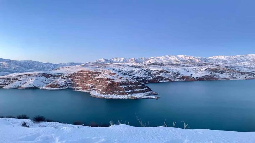 A snow-covered landscape with a large body of water and mountains in the background. 1