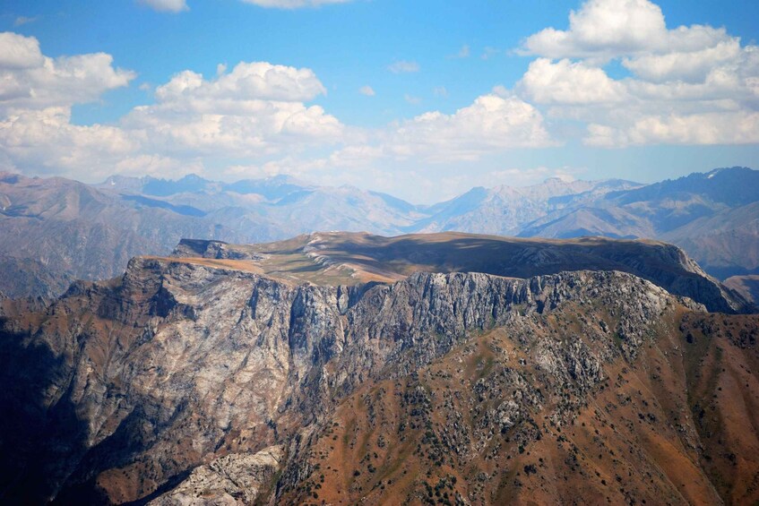 A mountainous landscape with rugged terrain and distant peaks under a partly cloudy sky. 5