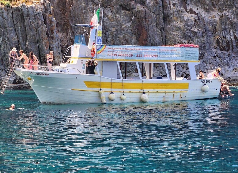 A boat named 'Arcobaleno' with people on board and some in the water. 5