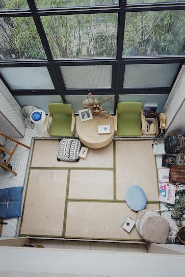 A cozy indoor seating area with a large tatami mat, green cushions, and a small round table with decorative items. 2