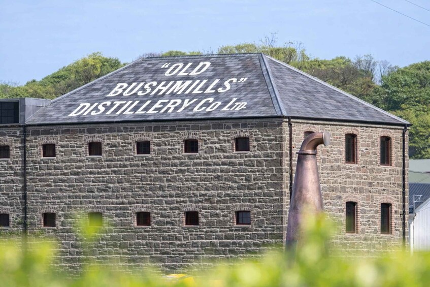 A stone building with the sign 'Old Bushmills Distillery Co. Ltd.' on the roof. 3