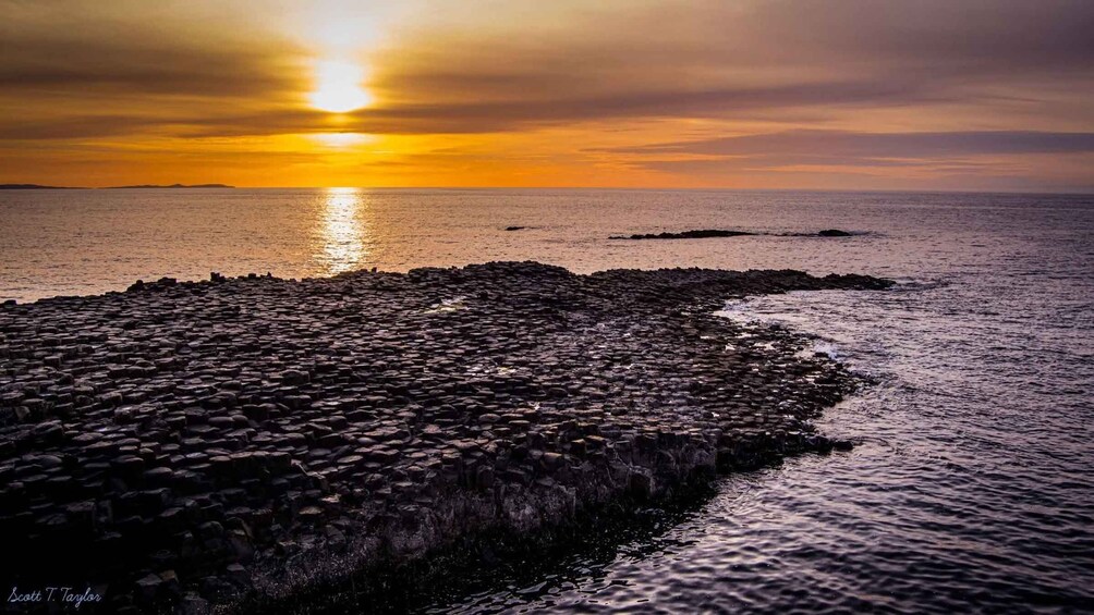 A sunset over a rocky coastline with waves crashing against the rocks. 4
