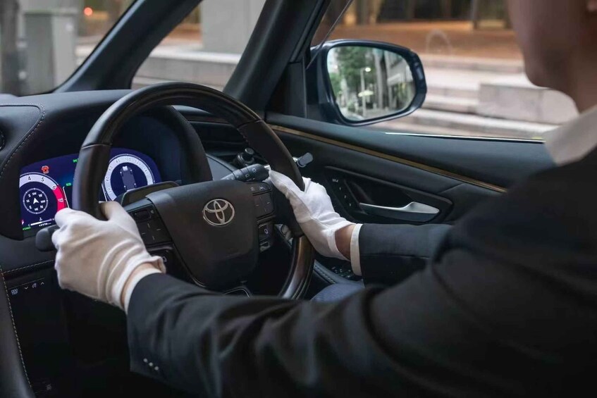 A person driving a car with a digital dashboard and steering wheel. 4