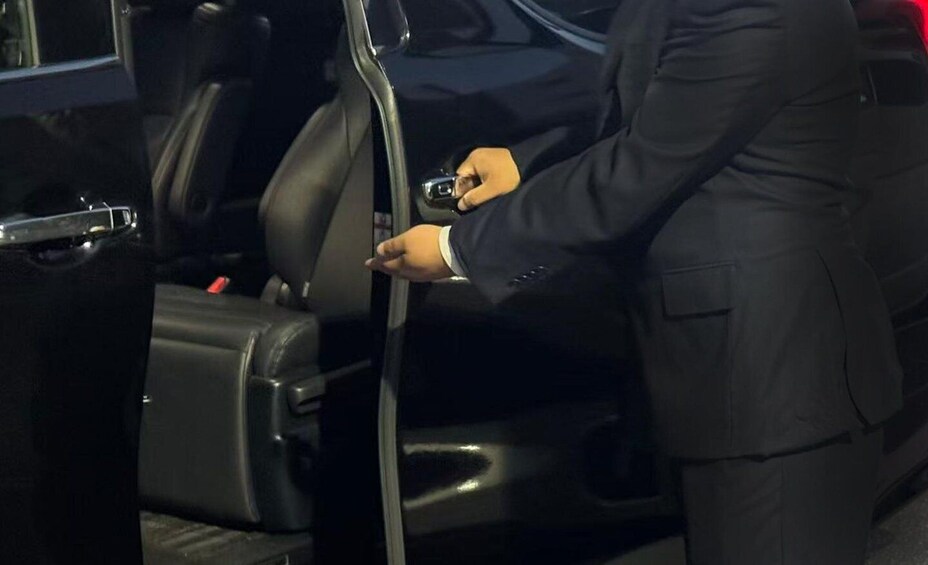 A person in a suit opening a car door. 3
