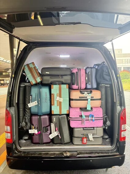 A van with its back doors open, packed with various suitcases and bags. 2