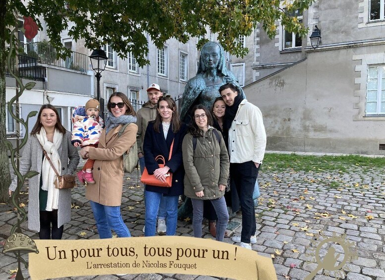 A group of people standing in front of a statue with a banner that reads 'Un pour tous, tous pour un!' and 'L'arrestation de Nicolas Fouquet'. 3