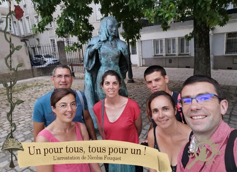 A group of people posing in front of a statue, with a cobblestone street and buildings in the background. 1