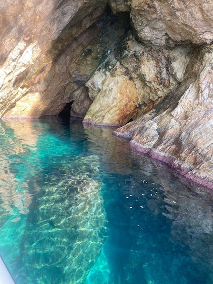 A cave with clear turquoise water and rocky walls. 3