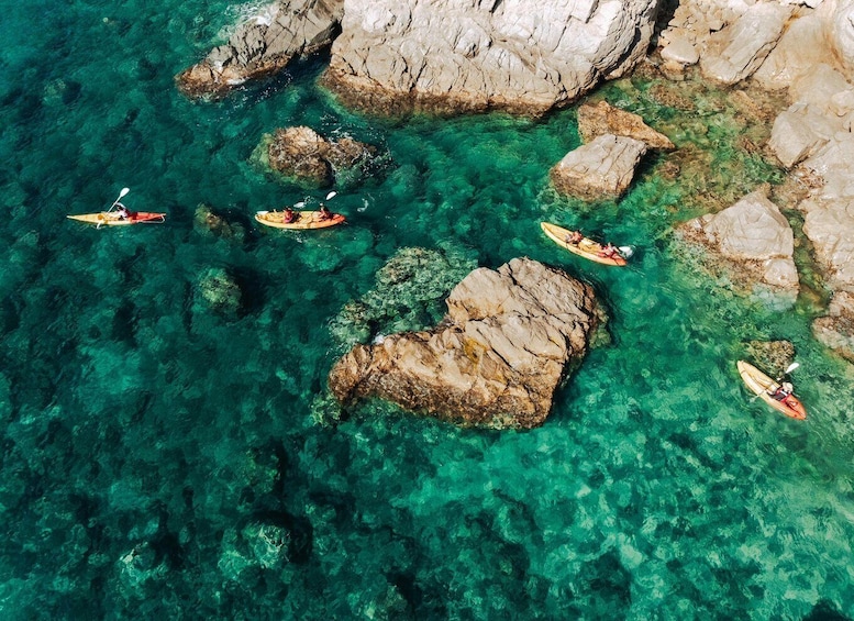 Kayakers navigating through clear turquoise waters with rocky formations. 1