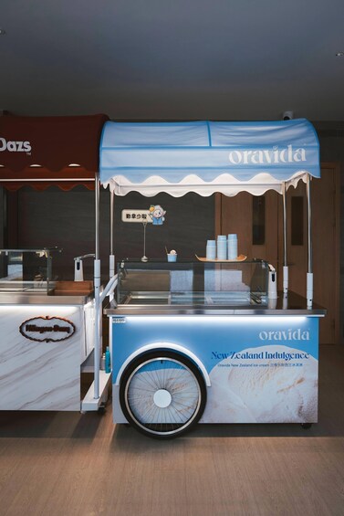 A blue ice cream cart with the brand name 'Oravida' and 'New Zealand Indulgence' written on it. 3