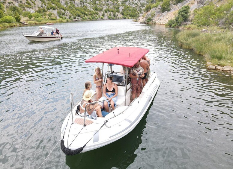 A small boat with a red canopy on a calm river surrounded by greenery. 4