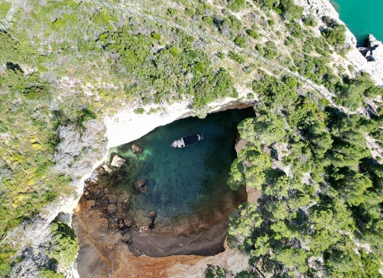 A coastal landscape with a clear blue sea, rocky shore, and dense greenery. 5