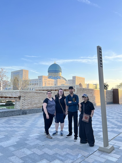A group of people standing in front of a building with a blue dome and a tall signpost. 1
