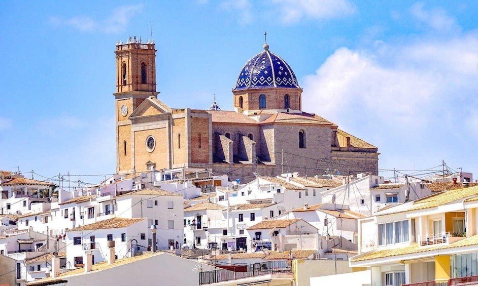 A historic church with a blue dome and bell towers, surrounded by white buildings with terracotta roofs. 3