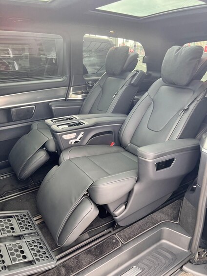 The interior of a vehicle with grey leather seats, a central console with cup holders, and a sunroof. 3