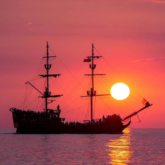 A ship with multiple masts sailing on the water during sunset. 1