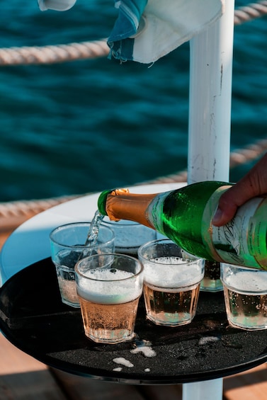 A hand pouring champagne into glasses on a table. 4