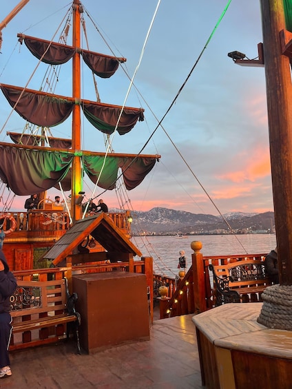 A wooden deck with a large ship's mast, a bench, and a railing. 5