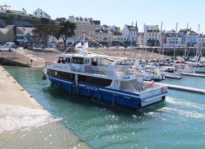 A blue and white boat named MOR BRAZ at a marina with other boats and buildings in the background. 1