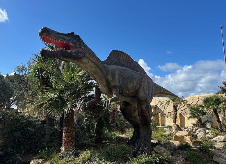 A life-sized dinosaur statue in a naturalistic setting with palm trees and rocks. 5