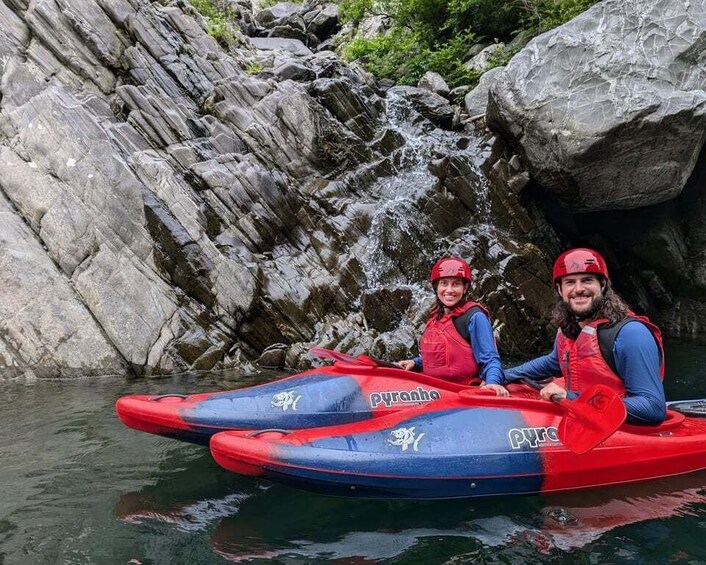 Two people in a red and blue inflatable raft with the brand 'Pyranha' on a calm river with rocky banks. 4