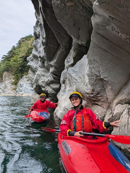 Two people kayaking in a narrow waterway between rocky cliffs. 5