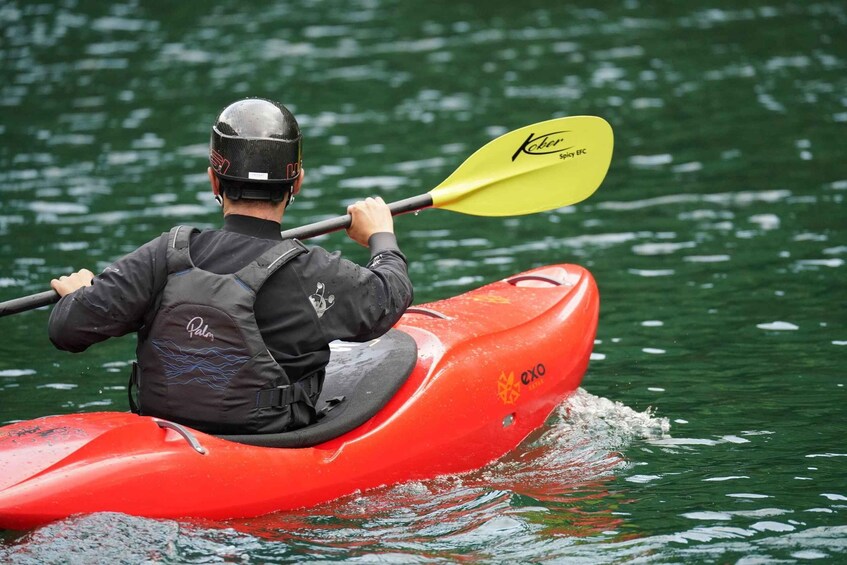 A person kayaking on a river in a red kayak. 3