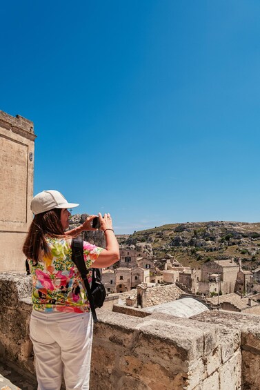 A person taking a photo of a historic town with stone buildings and ruins. 1